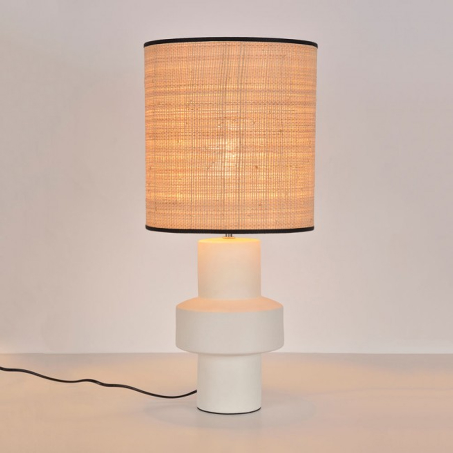 Lampe à poser Venus en céramique blanche avec abat-jour en fibre naturelle allumé, éclairant l'espace. Dakar, Sénégal