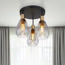Plafonnier Fanni 3 lampes allumées, créant une ambiance chaleureuse avec son design en métal laiton et verre fumé – Dakar, Sénégal.